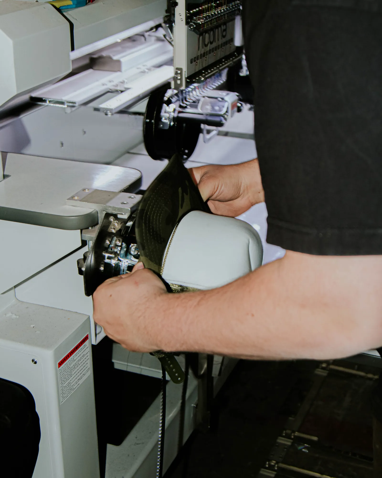 Embroidery machine stitching a custom hat at our Albuquerque shop