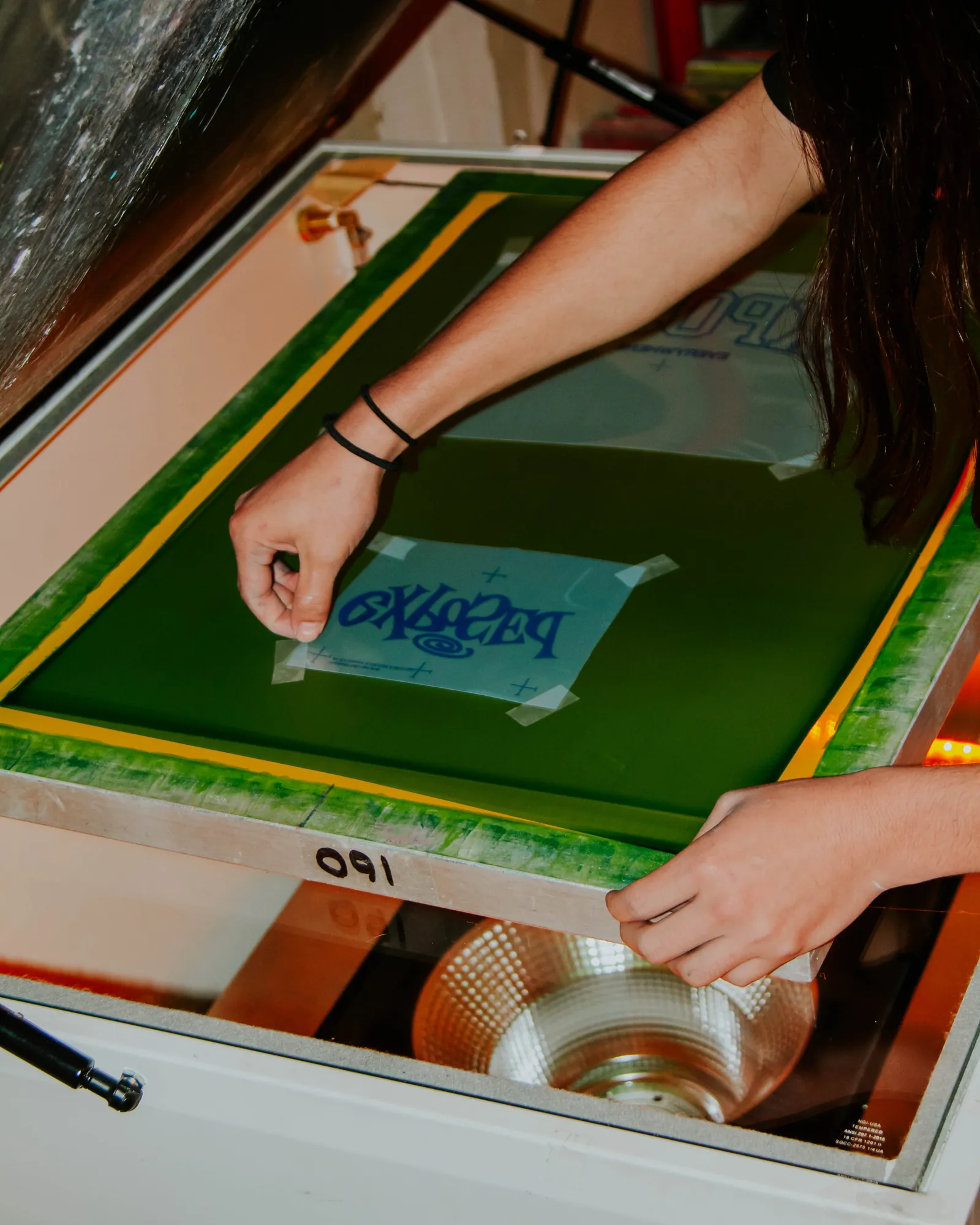 Hands taping a film positive onto a screen during pre-press prep