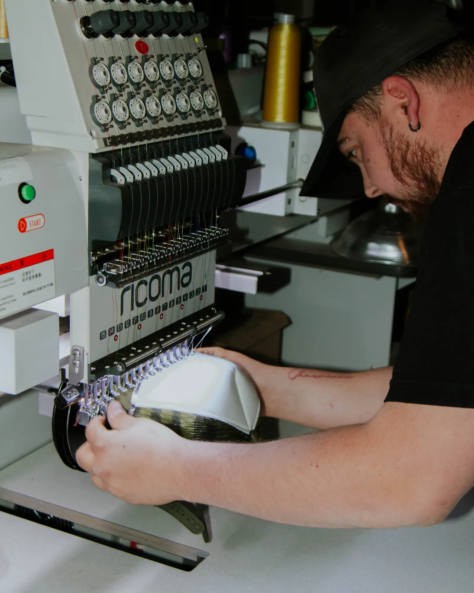 Ricoma embroidery machine stitching a design onto a white custom cap