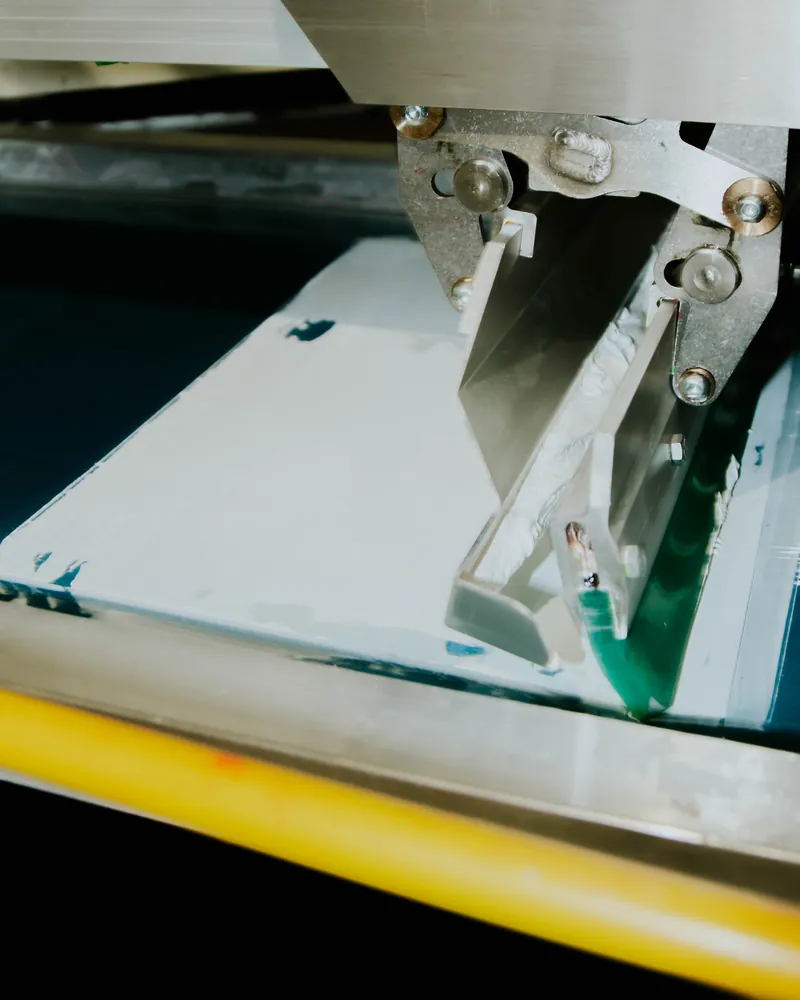 Closeup of a squeegee and press head on a screen printing press