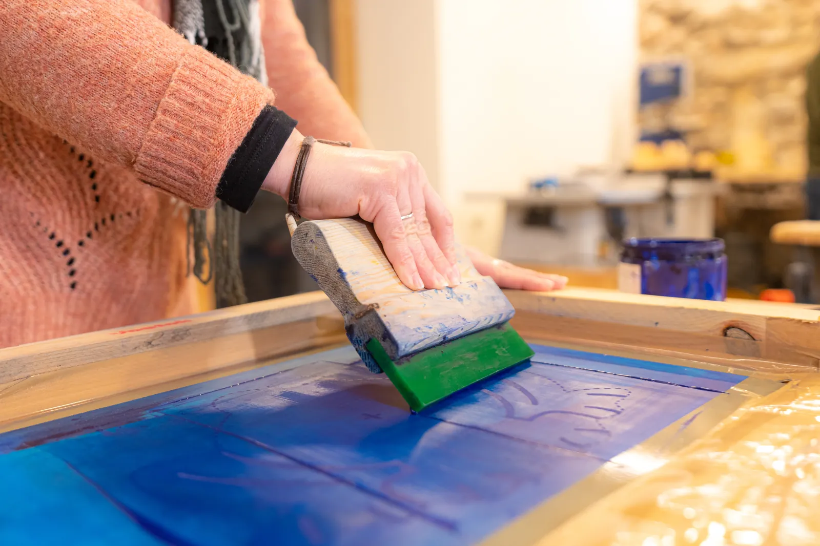 Squeegee pulling ink across a screen during screen printing