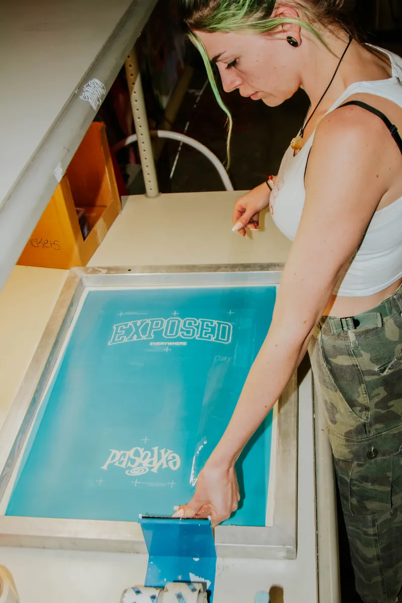 Printer rinsing a freshly exposed screen at the washout booth